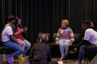 A tight shot of six people sitting in a circle having an in-depth conversation. 