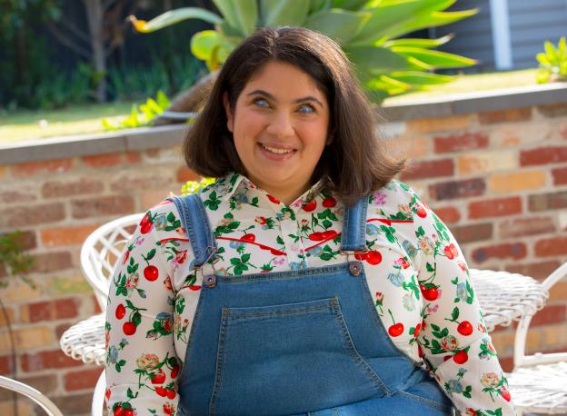 Olivia Muscatt smiling outside and wearing overalls